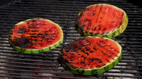Mehrere Scheiben Wassermelone liegen auf einem Grill.