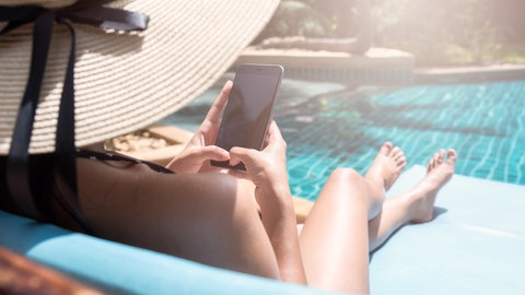 Frau nutzt Handy am Pool