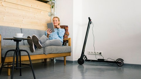Eine Frau lädt ihren E-Roller