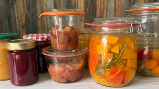 Apfelstücke im Glas, Pflaumenmarmelade und fermentiertes Gemüse