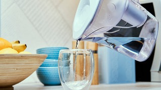 Wasser wird aus einem Trinkwasserfilter in ein Glas gegossen