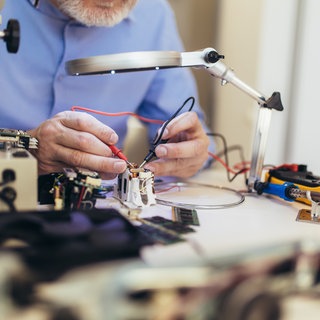 Mann in blauem Hemd repariert Elektronik. Wie wird sich das Recht auf Reparatur auf unseren Konsum auswirken? 