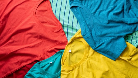 Shirts mit verschiedenen Farben liegen aufeinander gestapelt. Funktionsshirts aus Merino sollen eine optimale Wärmeregulation haben und geruchsneutral sein. Aber wie sieht es bei der Haltung der Tiere und Schadstoffen aus?