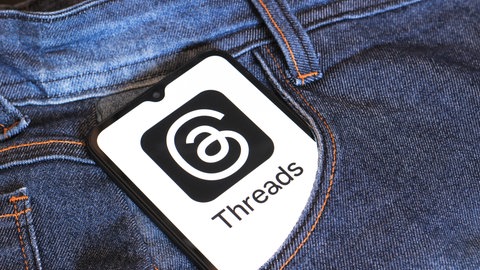 Ein Smartphone steckt in einer Tasche einer Jeans und zeigt das Threads-Logo