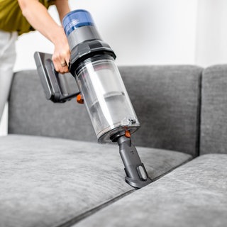 Handstaubsauger wird auf helles Sofa gehalten. Wir machen den Test: Bosch, Kärcher, Stihl, Mi, Lidl: Welcher Akku Handstaubsauger ist der beste?