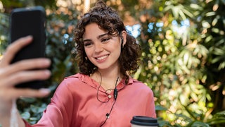 Junge Frau telefoniert mit einem Smartphone: Lauschen Apps wie Instagram, Facebook, Tiktok mit, wenn wir telefonieren - sodaß wir personalisierte Werbung bekommen? 