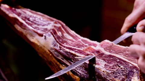 Ibérico Schinken wird mit einem Messer abgesäbelt. Echter Ibérico-Schinken ist eine Delikatesse. Wird in Deutschland minderwertige Ware verkauft?