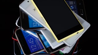 Ein Stapel mit mehreren alten Smartphones.