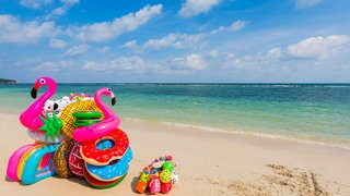 Bunte aufblasbare Schwimmhilfen in Form von Ringen, Flamingos undFrüchten am Strand: Flug-Flatrates oder Abos bei Reiseportalen versprechen günstige Urlaubs-Angebote. Man könne regelmäßgi viel Geld sparen. Verbraucherschützer warnen vor diesen Angeboten. 