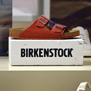 Birkenstock-Sandale steht auf Schuhkarton. Wie gut ist die Qualität von Birkenstock? Warum sind Birkenstocks so teuer geworden?