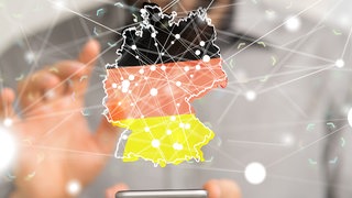 Mann vergrößert digitale Deutschlandkarte, in der sich viele Punkte vernetzen, in der Luft