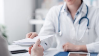 Hausärztin übergibt ein Rezept