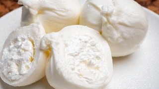 Zwei Burrata-Kugeln und eine halbierte Burrata. Wie gut ist Burrata von Supermarkt und Discounter? Unser Test zeigt, welche Produkte mit Geschmack und Qualität punkten – und wo der cremige Käse zu wünschen übriglässt.