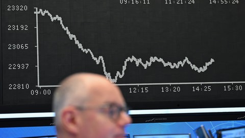 Ein Börsenhändler auf dem Parkett der Frankfurter Wertpapierbörse vor der Anzeigetafel mit der DAX-Kurve