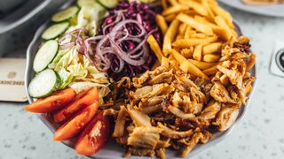 Dönerfleisch liegt neben Pommes und Gemüse auf einem Teller. Wie gut ist Döner aus dem Kühlregal im Supermarkt oder Discounter?