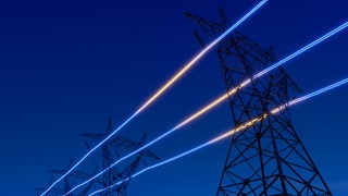 Strommasten vor einem satten mittelblauen Himmel, zerteilt durch leuchtende Kabel. Der neue Industriestrompreis soll in Deutschland energieintensive Unternehmen entlasten. Firmen leiden unter hohen Energiekosten. Doch hilft die Subvention wirklich?