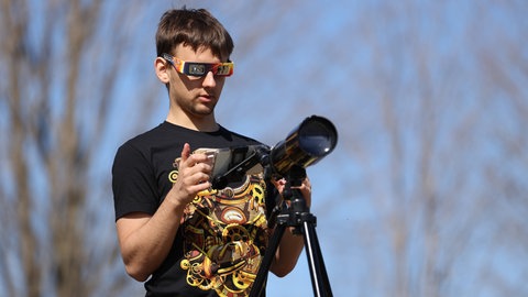 Gut ausgerüstet für die Beobachtung der Sonnenfinsternis: spezielle Sonnenfinsternisbrille zum Schutz der Augen, Filter für Handykamera und Teleskop.