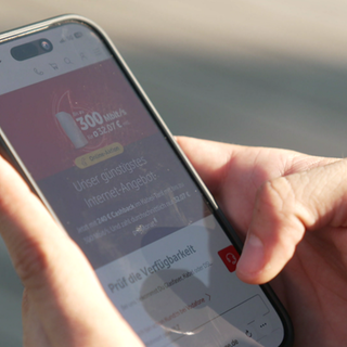 Zu sehen sind Hände, die ein Handy halten. Auf dem Bildschirm ist ein Werbeangebot von Vodafone zu sehen.  