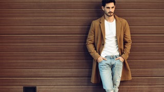 Mann in Jeans, T-Shirt und Mantel