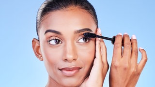 Frau tuscht sich die Wimpern mit Wimperntusche
