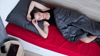 Einschlafen bei Hitze: Eine Frau liegt im Bett und kann nicht schlafen