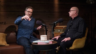 Florian Weber gestikuliert mit seiner Hand, Christian Peter Dogs schaut dabei zu.