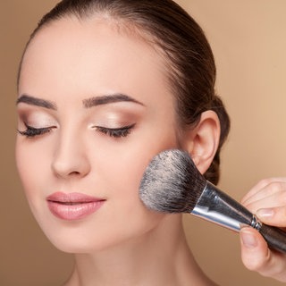 Frau wird mit Pinsel geschminkt