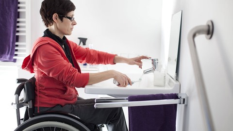 Frau mit Rollstuhl beim Zähneputzen