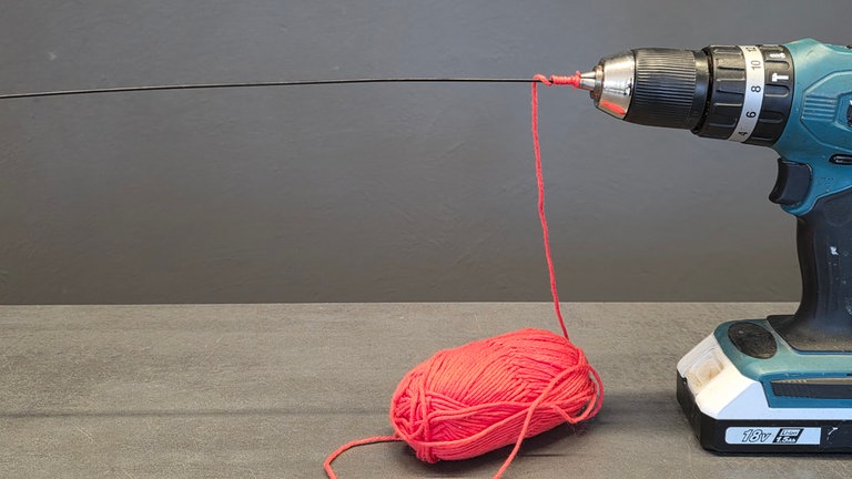 Den Draht in die Bohrmaschine einspannen und dabei gleich die Wolle mit einklemmen.
