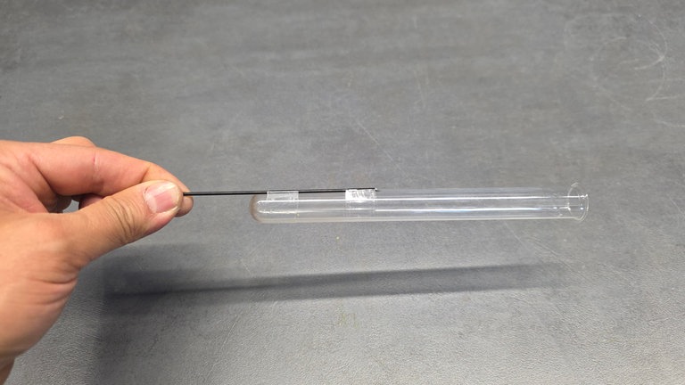 An die Reagenzgläser werden mit dem Klebeband je ein Stück schwarzer Steckdraht an zwei Stellen geklebt. 