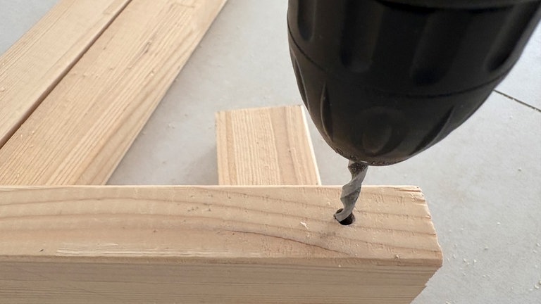 An beiden horizontalen Seiten der Holzleiste jeweils ein Loch bohren.