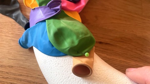 Die Luftballons nach und nach in unterschiedlichen Richtungen über den Styroporreifen legen und überlappend mit den Stecknadeln feststecken. 
