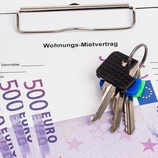 Wohnungs-Mietvertrag mit Schlüssel, Stift und mehreren 500 Euro Scheinen.