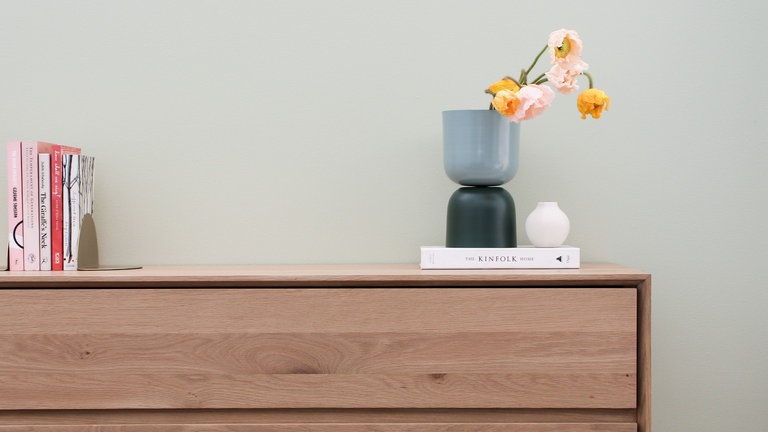 Ein kleiner Schrank mit Schubladen, der vor einer Wand steht