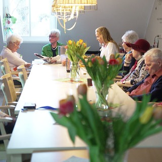 Ältere Menschen sitzen gemeinsam an einem Tisch.