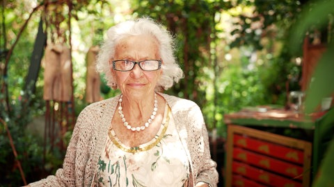 Elisabeth Gateff steht im Garten und sieht in die Kamera