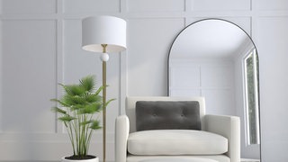 Ein gemütliches modernes Zimmer mit Sessel, Stehlampe, Topfpflanze und Spiegel.