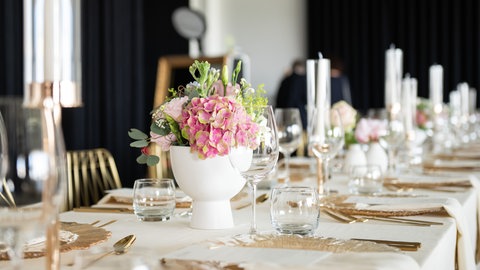 Gedeckter Tische für eine Hochzeitsfeier mit goldenen Tellern und goldenem Besteck.