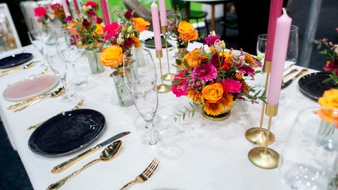 Ein gedeckter Tisch für eine Hochzeitsfeier mit pink- und orangefarbenen Blumen.