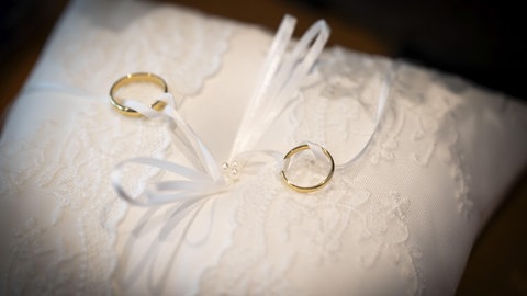 Eheringe auf einem weißen Kissen mit Spitze.