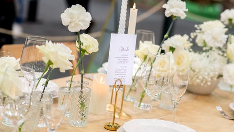 Ein gedeckter Tisch für eine Hochzeitsfeier mit weißen Blumen.