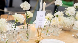Ein gedeckter Tisch für eine Hochzeitsfeier mit weißen Blumen.