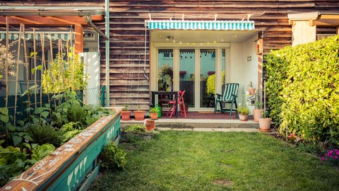 Ein kleiner Garten mit Rasen und Terrasse hinter einem Reihenhaus.
