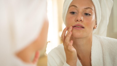 Junge Frau schaut in den Spiegel