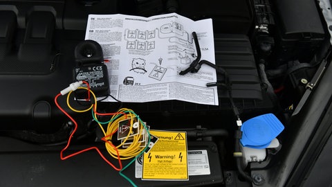 Eine Marderschreck bei der Installation im Motorraum von einem Auto: Den Einbau solcher Vergrämungs-Geräte sollte ein Fachmann durchführen, damit die Abwehr von einem Marder gelingt.