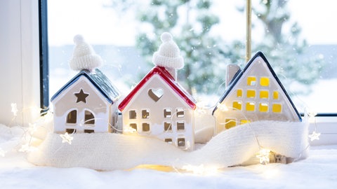 Weihnachtsdeko im Fenster: Kleine Häuser mit Lichterkette.