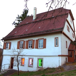 Das alte Pfarrhaus in Bettringen steht unter Denkmalschutz. Das weiße Haus ist mehrstöckig, hat Fensterläden und ist mit Biberschwanzziegeln gedeckt.