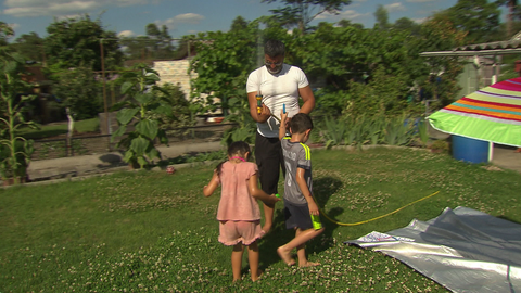 Ein Vater spielt mit seinen Kindern in einer Kleingartenanlage
