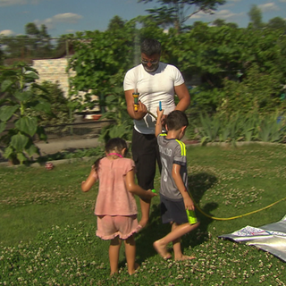 Ein Vater spielt mit seinen Kindern in einer Kleingartenanlage