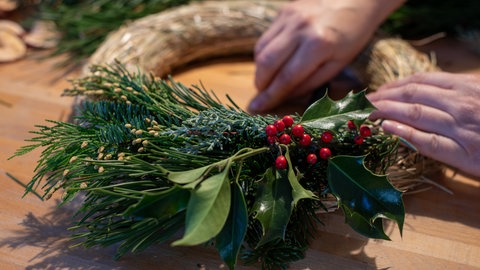 Nachhaltigen Adventskranz basteln: Ein Frau bindet einen Adventskranz.